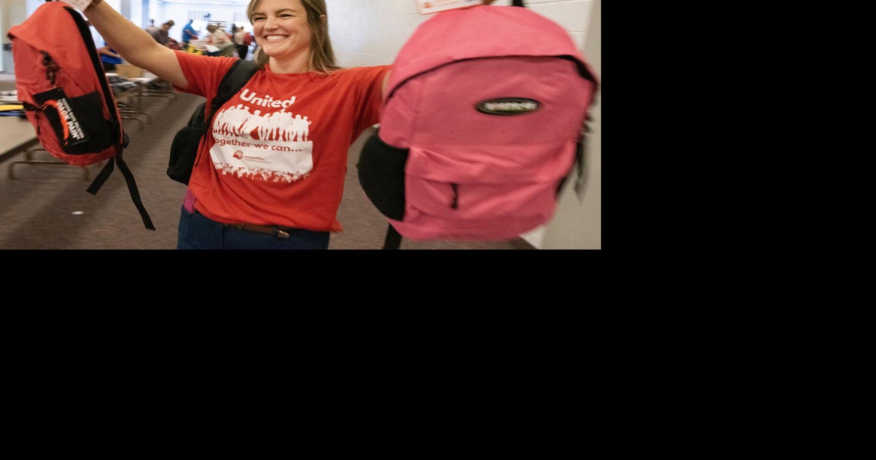 Volunteers stuff backpacks with school supplies