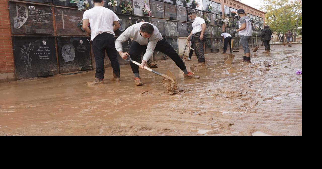 Mudcaked volunteers clean flood debris in a Spanish town as