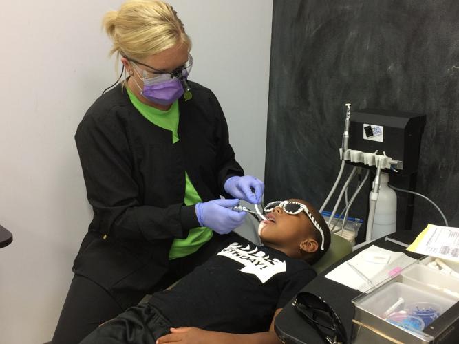 Mobile dentists exam, clean teeth of youth at community Back-to-School Bash