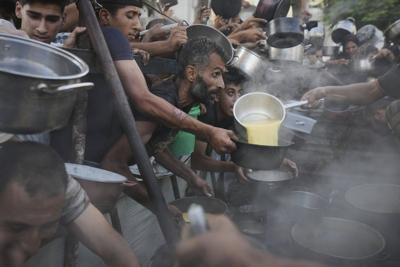Photos of desperate Palestinians reaching for food in Gaza as experts warn of famine