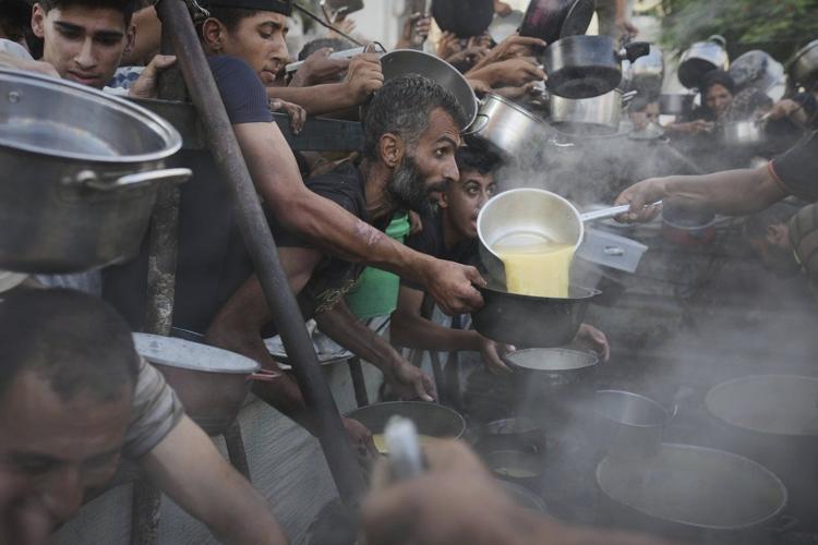 Photos of desperate Palestinians reaching for food in Gaza as experts warn of famine