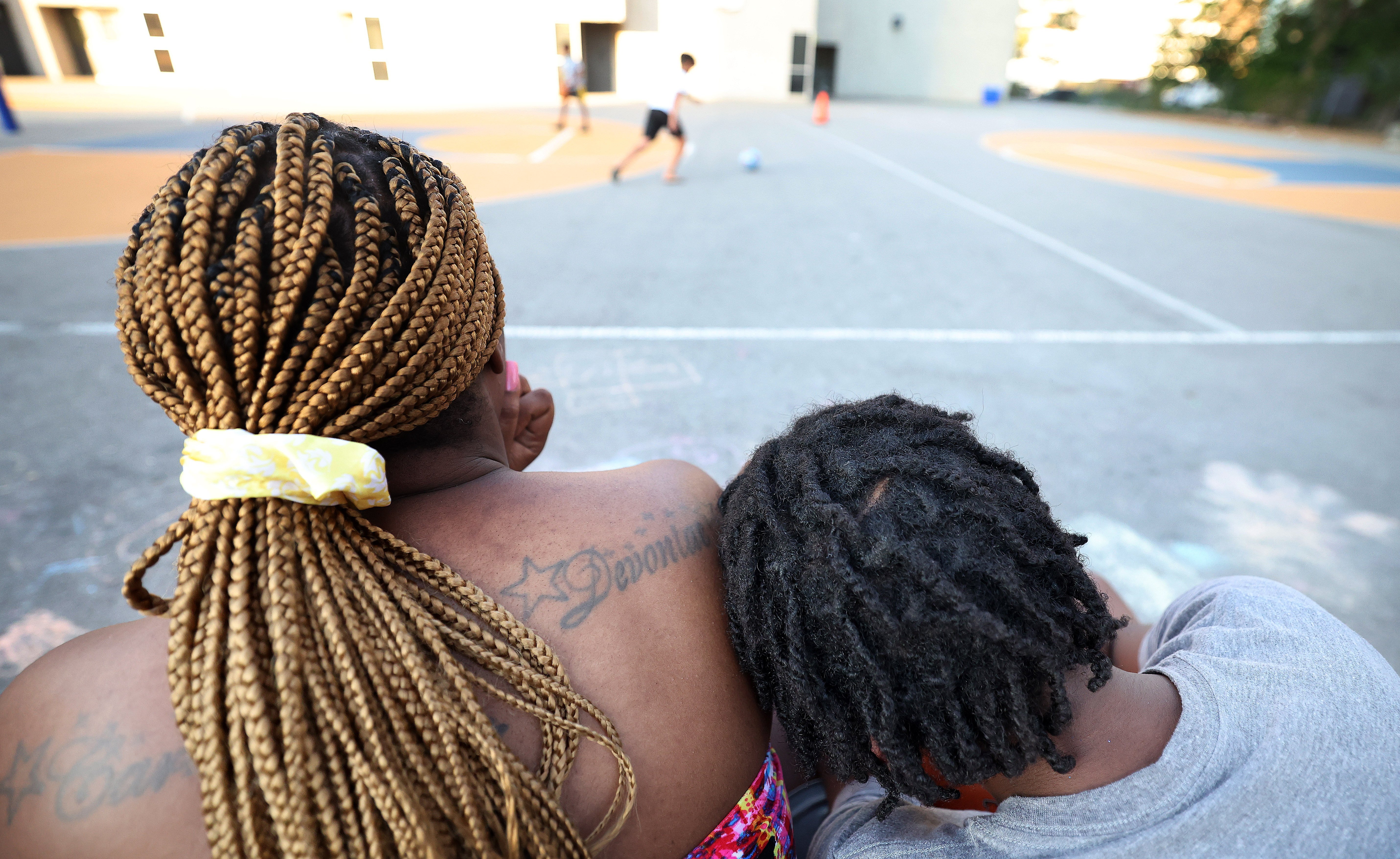 A photo of a woman and a boy taken from behind. The woman's tatoo reads 'Devontae'