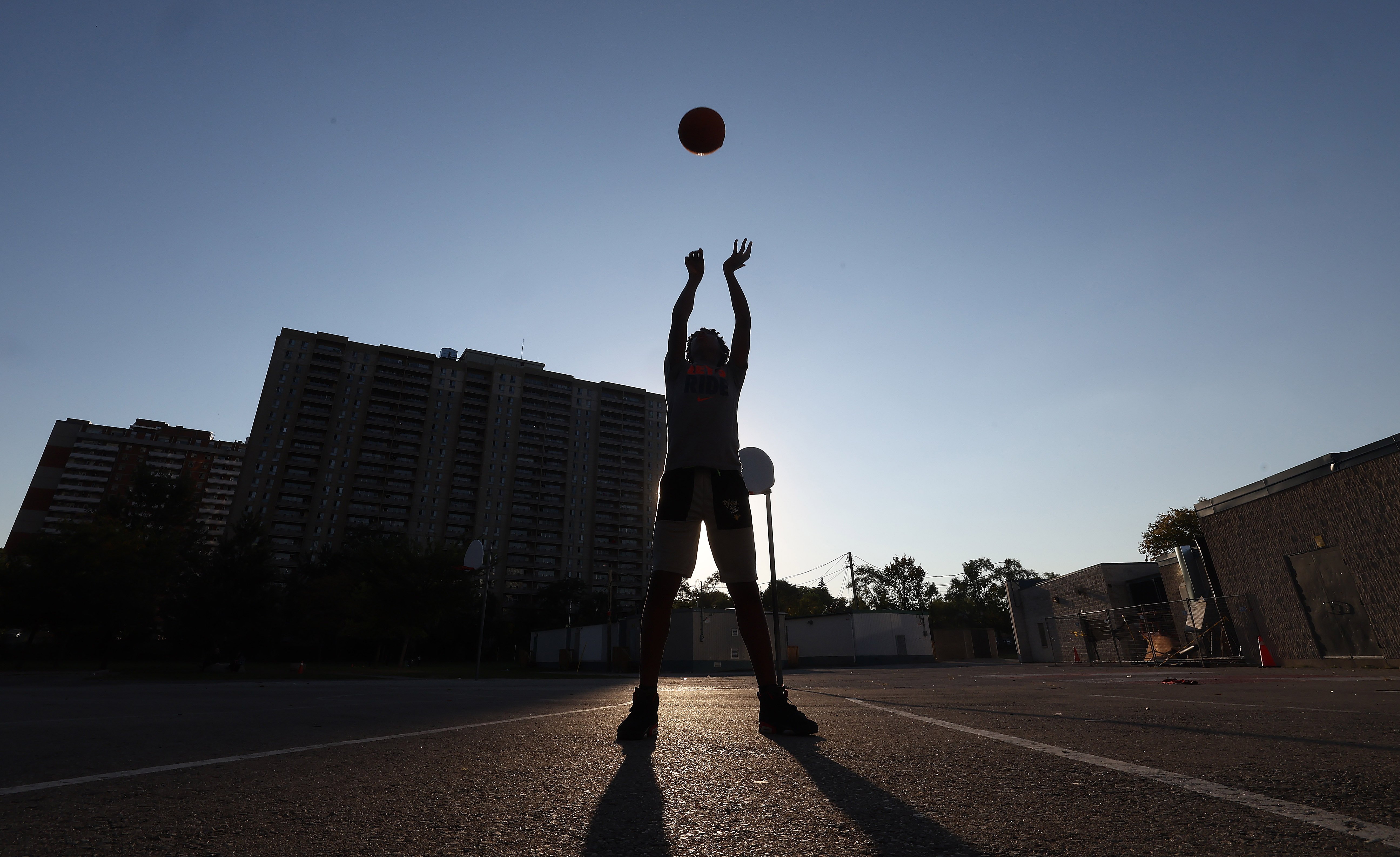 The silhouette of a boy shooting a basketball