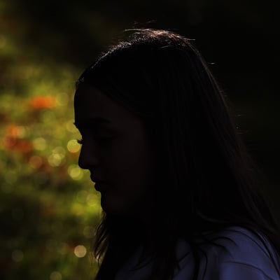 A photo of a girl with long hair. Her face is obscured by shadows