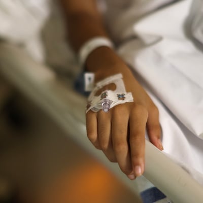 A young girls hand with an IV in a hospital bed