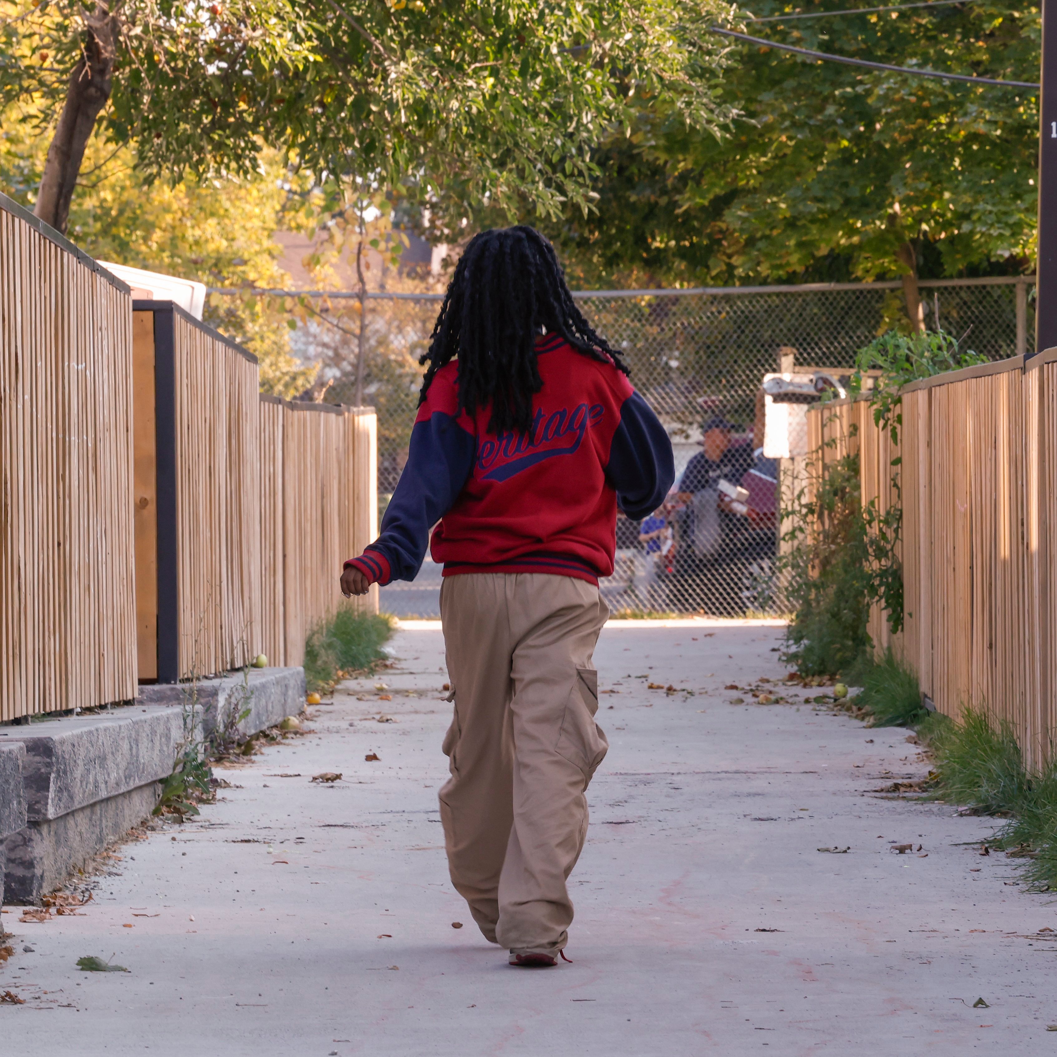 A photo of a young girl鈥檚 back. The girl is walking down a laneway.