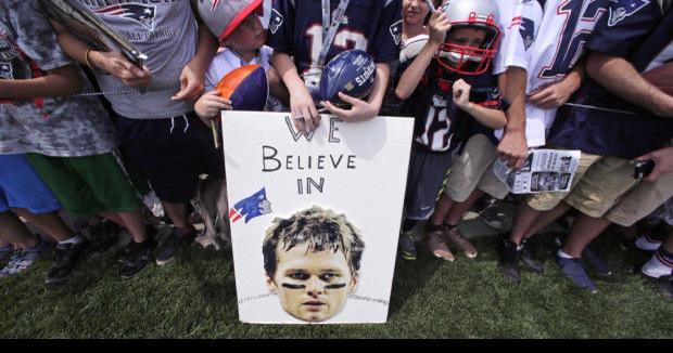 New England Patriots quarterback Tom Brady (12) wipes the sweat