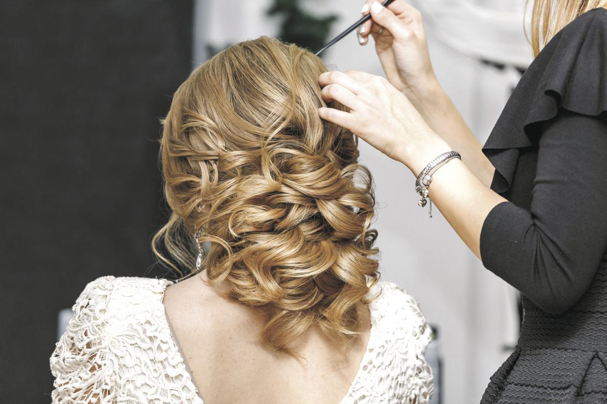 Young bride getting her hair done before wedding by professional