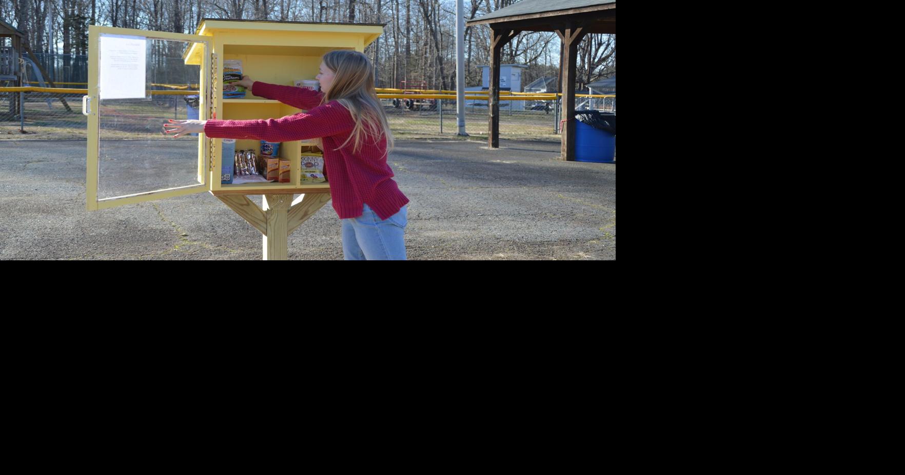 مراهق يشرف على خزانة طعام مجانية مستقلة.