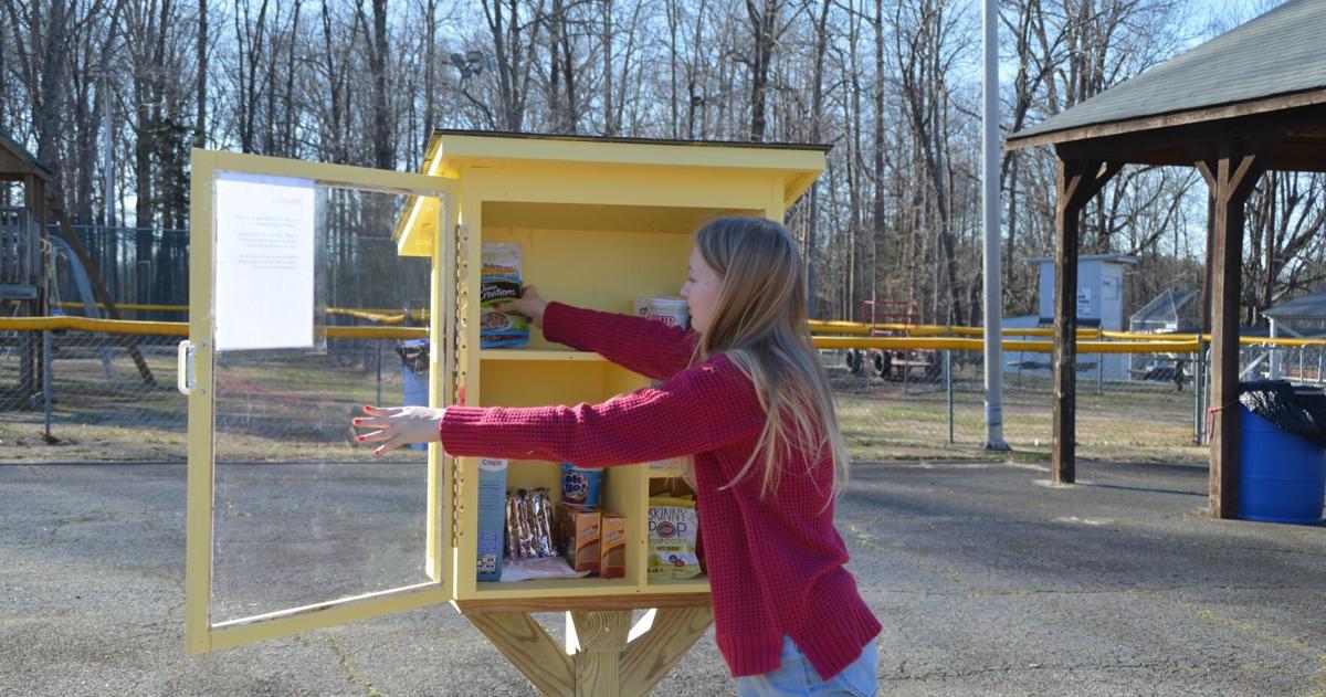 مراهق يشرف على خزانة طعام مجانية مستقلة.