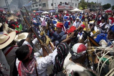 Mexicans representing indigenous soldiers and the French army, re-enact the battle of Puebla during Cinco de Mayo celebrations in Mexico City.