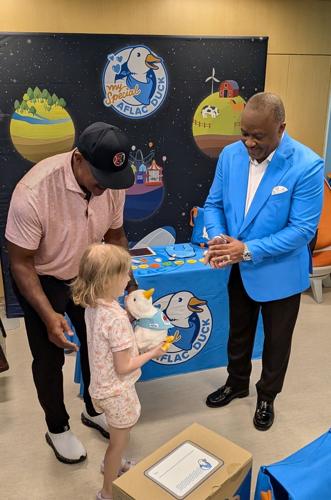 Former professional baseball and football player Brian Jordan (l) and Aflac Incorporated and Aflac U.S. President Virgil Miller (r) hand a My Special Aflac Duck to Leighton, a six year old patient at SSM Health Cardinal Glennon Children's Hospital in St...
