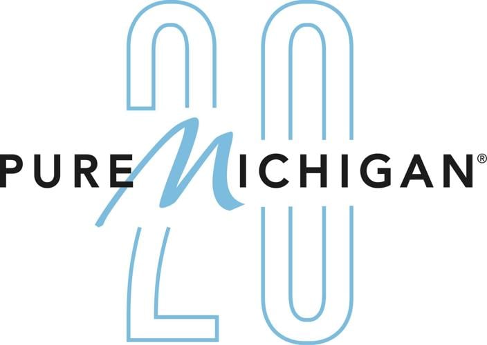 Pure Michigan 20th anniversary logo. The word "Pure" is in black sans-serif type, followed by the word "Michigan." The "M" is in a light blue script with the rest of the word "Michigan" in the same black sans-serif font. A large, stylized number 20 in l...