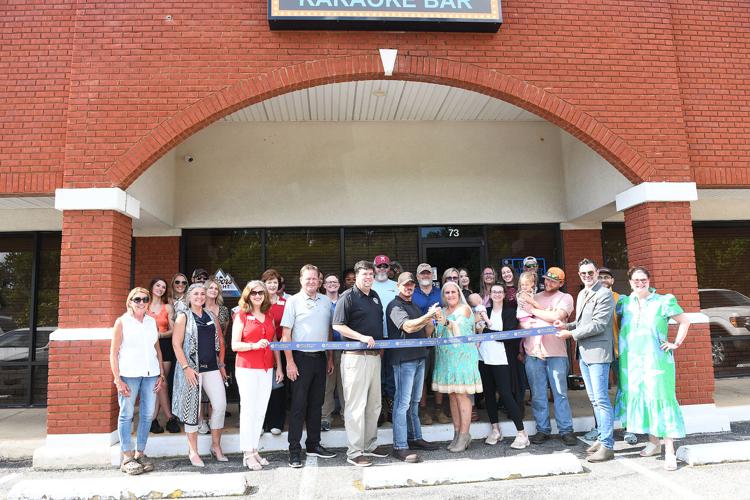 Cliff Williams / TPI Local officials and family of Michelle and Don Johnson gather with representatives of the Millbrook Chamber of Commerce for the ribbon cutting of Betty Anne’s Karaoke.