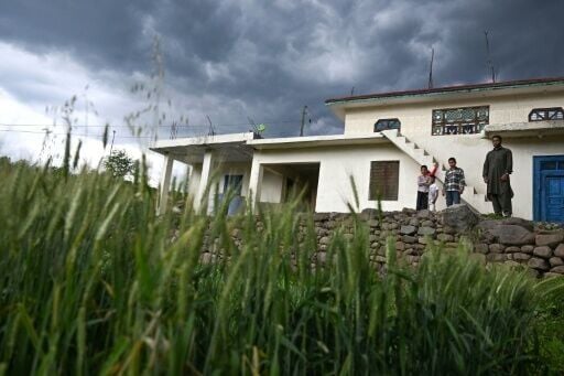 Mohammad Rashid (R) standing outside his house with a newly-built private bunker