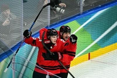 Nathan Mackinnon (L) celebrates scoring Canada's late winner over Finland at the 2026 Winter Olympics