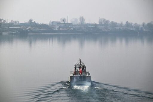 People take in the views of the North Korean town of Sinuiju (back) from a tour boat on the Yalu River in the border city of Dandong