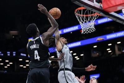 Devin Vassell of the San Antonio Spurs dunks the ball against Drake Powell in the Spurs' NBA victory over the Brooklyn Nets