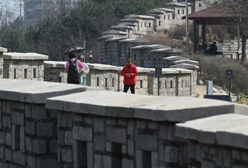 People walk along the fortress wall at Naksan Park in Seoul on March 17, 2026