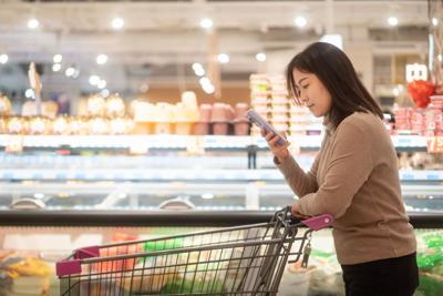 asian female using smart phone in supermarket