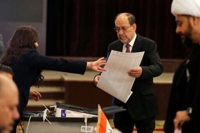 Former Iraqi prime minister Nouri al-Maliki holds the ballot paper at a polling station in Baghdad on November 11, 2025 during parliamentary elections