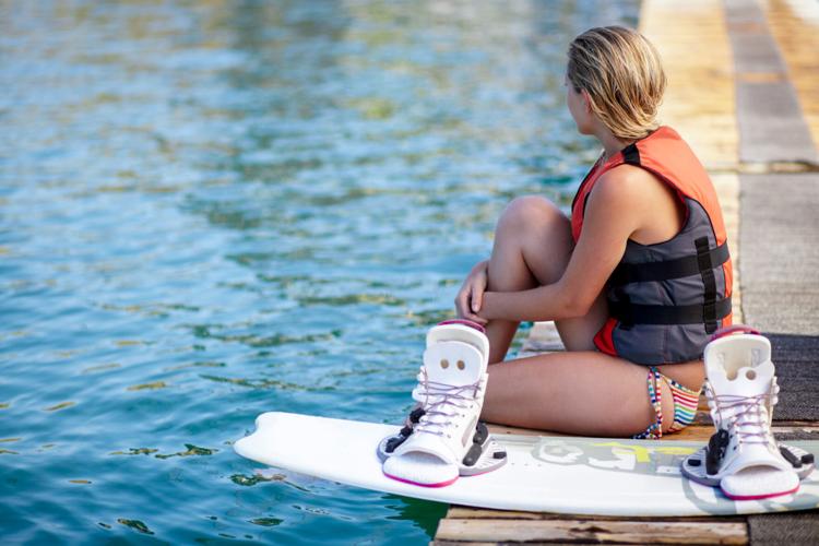 Woman, ready or wakeboard by water, lake or ocean sea with ideas, vision and planning fitness hobby. Person, life jacket and thinking athlete with swimsuit, exercise and training equipment for sports