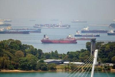 A container ship sails past oil tankers anchored in Singapore