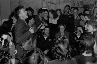American folk musician Pete Seeger sings and plays banjo for a group of people that includes first lady Eleanor Roosevelt in 1944.