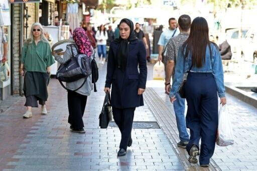 Iranian women walk along a busy street in Tehran