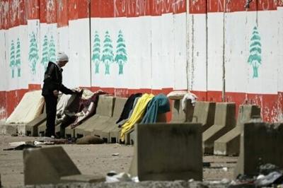 A man lays out his laundry at a parking lot in Beirut where people displaced by Israel have set up tents, on March 22