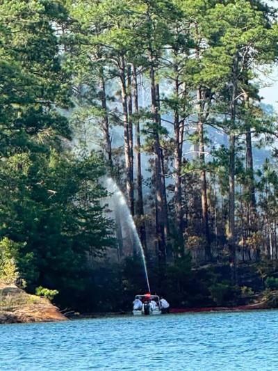 Halmar Gamez / Special to TPI Water is applied to a fire on Goat Island on Lake Martin Sunday evening. According to Elmore County Sheriff Bill Franklin, the fire is under control.