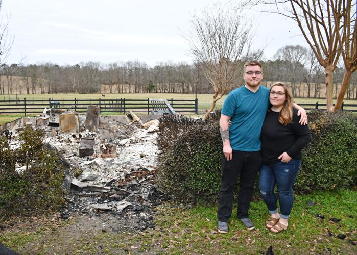 Cody and Autumn Buzby Pose in front of the remains of their home