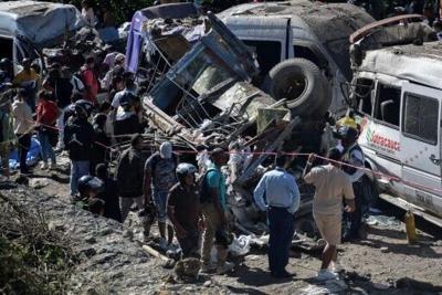 People stand next to vehicles destroyed in a deadly bomb attack on a highway in Cauca department in southwestern Colombia