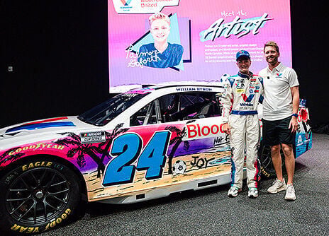 Twelve-year-old Palmer Goforth stands with William Byron in front of the special No. 24 Valvoline Chevrolet paint scheme designed by Goforth. A blood cancer survivor, Goforth’s design encourages joy and to “stay strong” while showcasing his “Miami vibes...