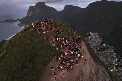Tourists watch the sunrise from Morro Dois Irmaos above the Vidigal favela