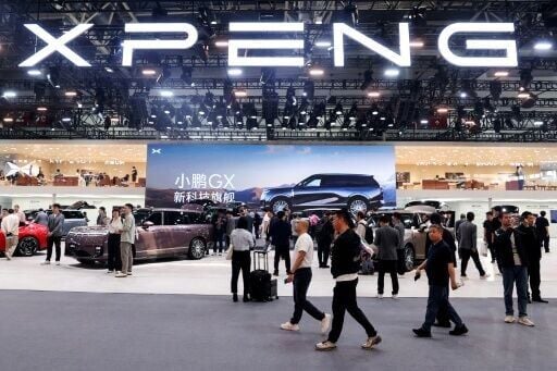 Visitors walk past the booth of Chinese automaker XPeng at the Beijing Auto Show