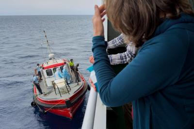 Passengers on the the hantavirus-stricken cruise ship MV Hondius watch epidemiologists board the boat in Praia, Cape Verde, on May 6, 2026 AP Photo/Uncredited