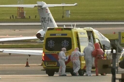 A person in a hazmat suit (2R) is escorted to an ambulance at Schiphol airport near Amsterdam on May 6, 2026