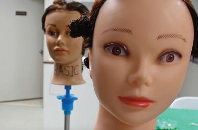 In cosmetology class, students do hair and nails on dolls, plastic fingers and each other