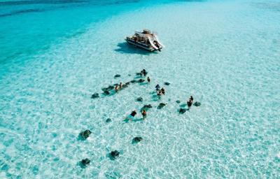 Clear blue waters with people swimming near boat
