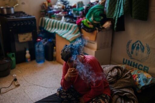 A displaced woman smokes a cigarette in a room at a school serving as a shelter for displaced people in the southern Lebanese city of Tyre