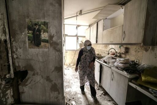 An Iranian woman walks through the destroyed kitchen in a home following a military strike in the Iranian capital Tehran on March 15, 2026