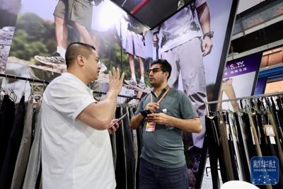 A foreign merchant talks with an exhibitor during an exhibition held in Shishi Clothing City of Quanzhou, Fujian Province in southeast China on April 18, 2026. (Xinhua/Jiang Kehong)