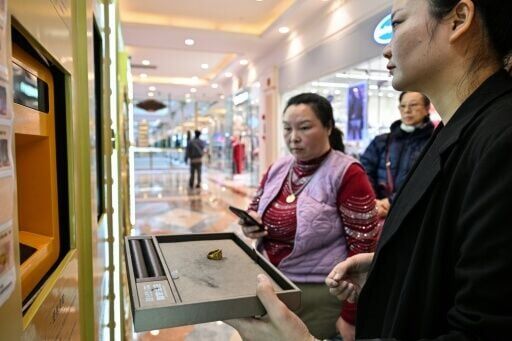 An attendant at the Shanghai mall helps sellers deposit ornate pendants, hammered rings and commemorative coins into an opening in the device