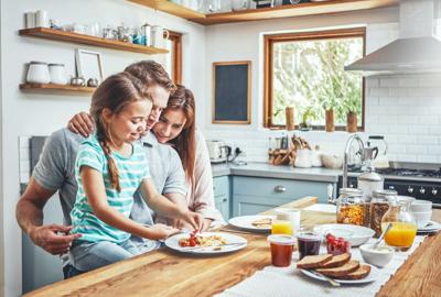 Morning, breakfast pancakes and happy family with children, mother and father, bonding and prepare ingredients. Food love, cooking and hungry woman, man and daughter in home kitchen eating meal