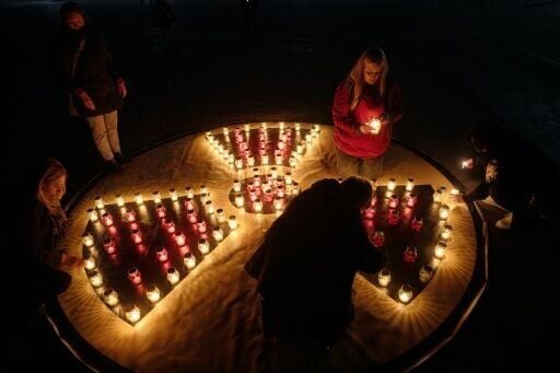 People light candles set in shape of a radiation sign in front of a memorial for Chernobyl victims in the town of Slavutych
