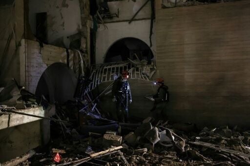 First responders inspect the site of an Iranian missile strike in Arad early on March 22, 2026