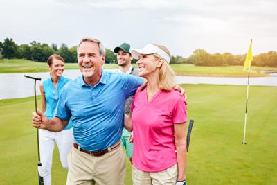 Happy, mature couple and golf outdoor with friends for fitness challenge, talking or support of hobby training. Smile, people and hug with love for game practice, bonding and relax on vacation course