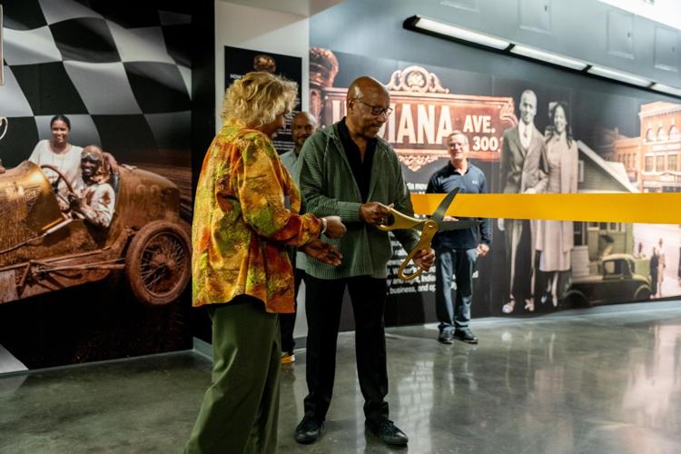 Guest Curator and retired General Motors chief of design Ed Welburn cuts the ribbon alongside Angi Rogers, the great niece of Charlie Wiggins.