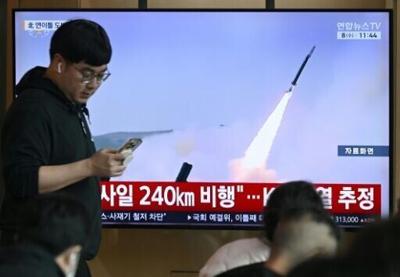 A man walks past a television screen showing a news broadcast with file footage of a North Korean missile test, at a train station in Seoul on April 8
